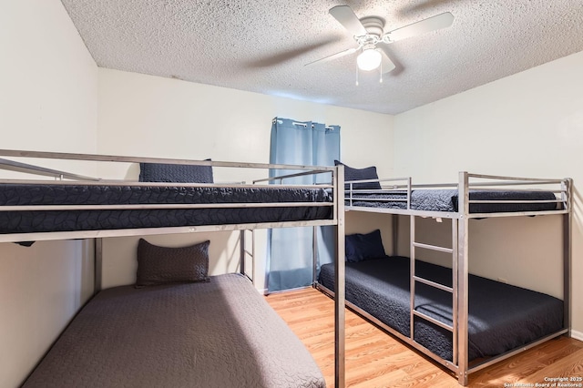 bedroom with a ceiling fan, a textured ceiling, and wood finished floors