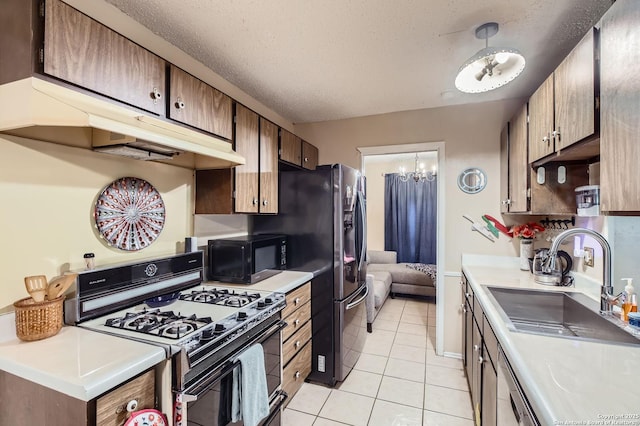 kitchen featuring black microwave, a sink, a textured ceiling, under cabinet range hood, and gas range oven