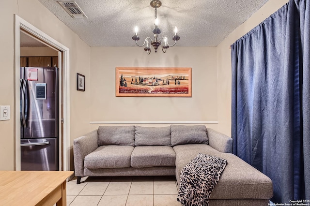 living area with light tile patterned flooring, a textured ceiling, a notable chandelier, and visible vents