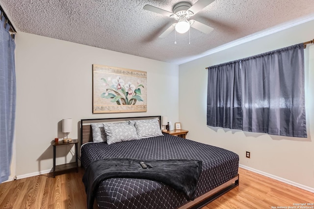 bedroom featuring baseboards, a ceiling fan, a textured ceiling, and wood finished floors