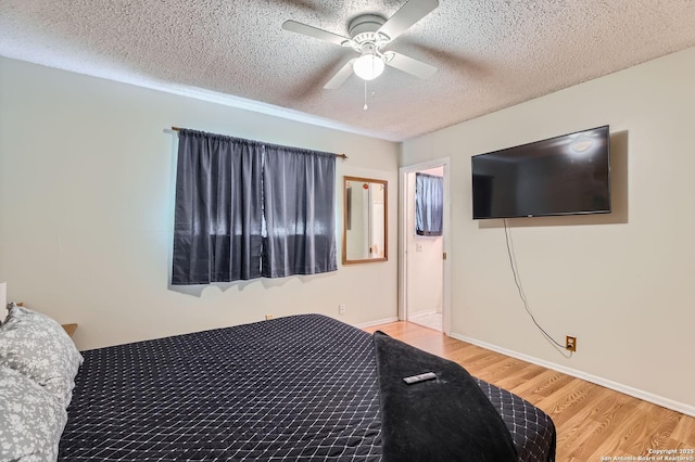 bedroom featuring light wood-type flooring, a ceiling fan, and a textured ceiling