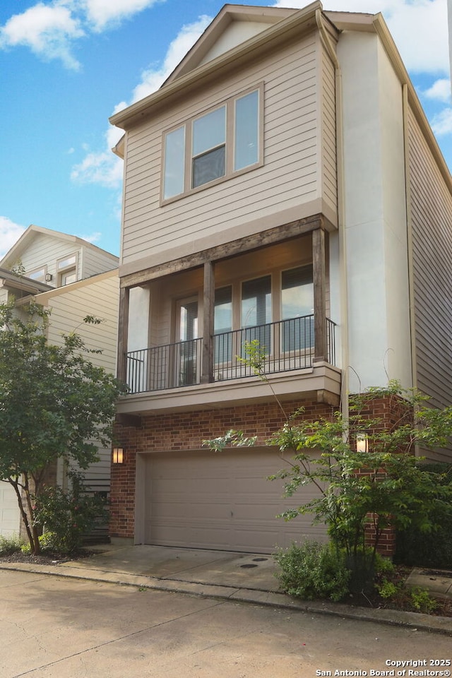 view of front facade featuring a garage, brick siding, a balcony, and driveway