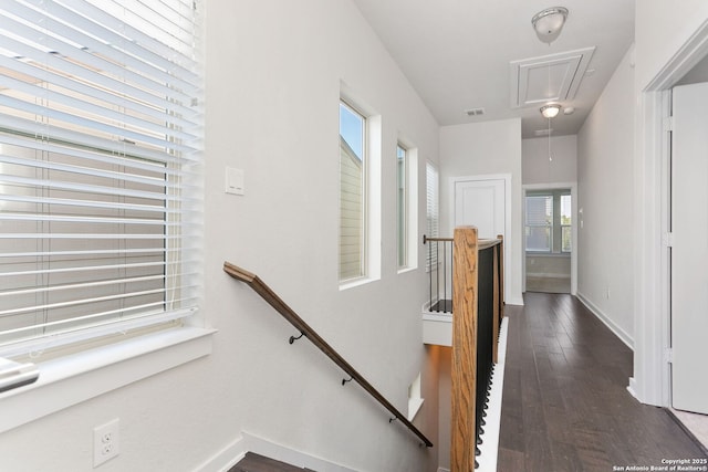 stairs featuring attic access, wood finished floors, and baseboards