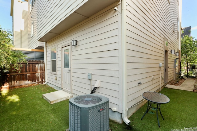back of property featuring fence, cooling unit, and a yard