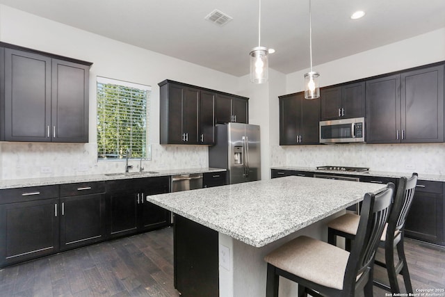 kitchen featuring a sink, stainless steel appliances, dark wood-type flooring, a breakfast bar area, and visible vents