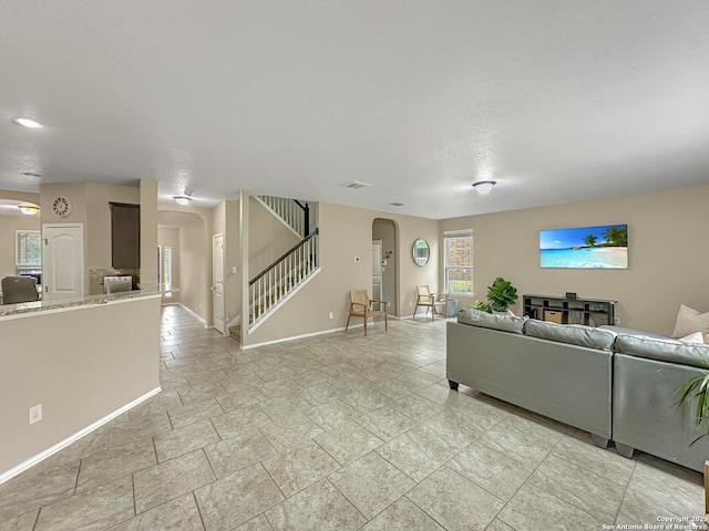 living room with baseboards, visible vents, arched walkways, and stairs