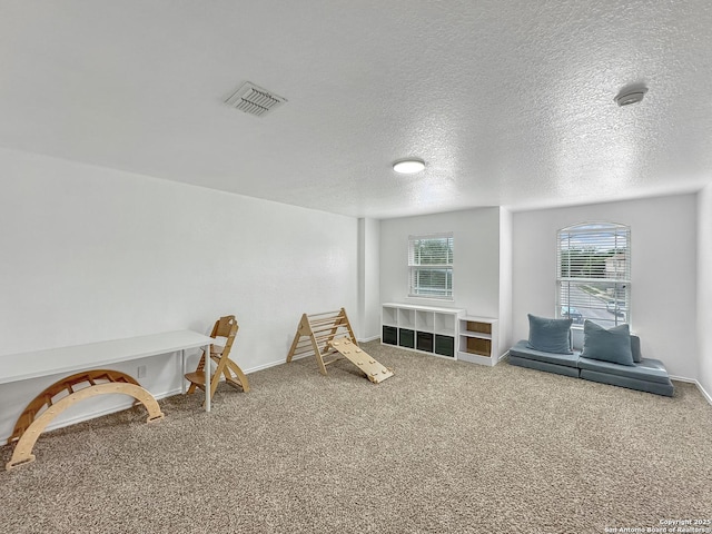 recreation room featuring a textured ceiling, visible vents, carpet, and baseboards