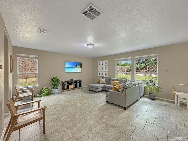 living room featuring baseboards, visible vents, and a textured ceiling