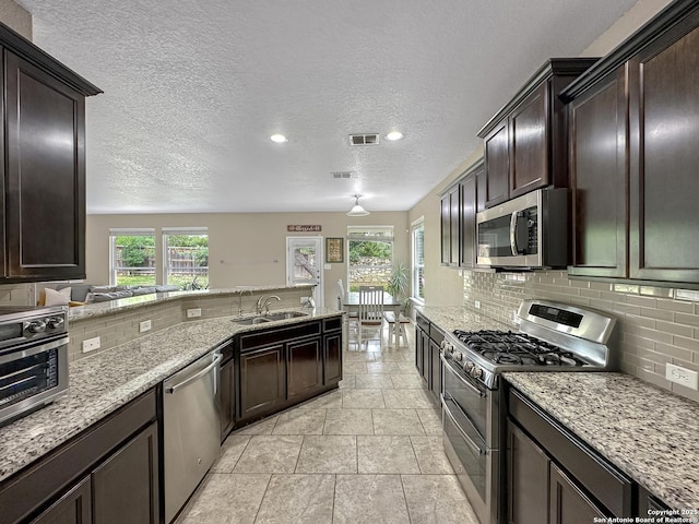 kitchen featuring stainless steel appliances, backsplash, plenty of natural light, and a sink