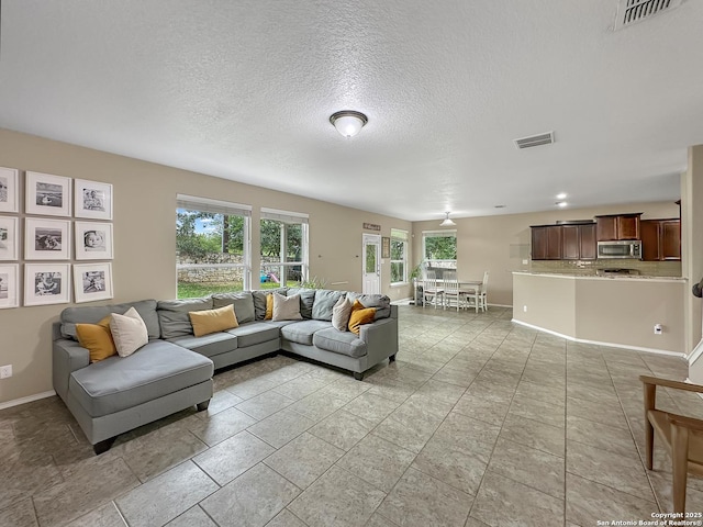 living room featuring a textured ceiling, visible vents, and baseboards
