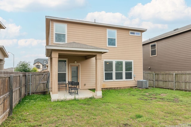 rear view of property with a lawn, a fenced backyard, central AC unit, and a patio area