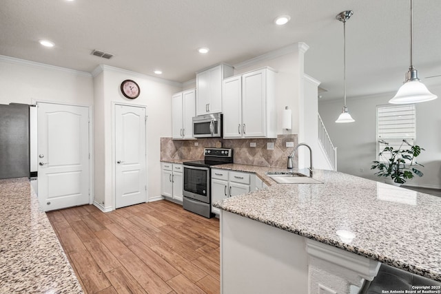 kitchen featuring a sink, stainless steel appliances, a peninsula, white cabinetry, and ornamental molding