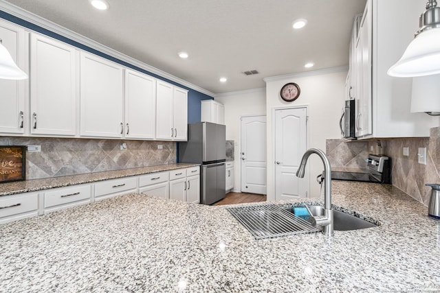 kitchen with decorative backsplash, stainless steel appliances, ornamental molding, a sink, and visible vents
