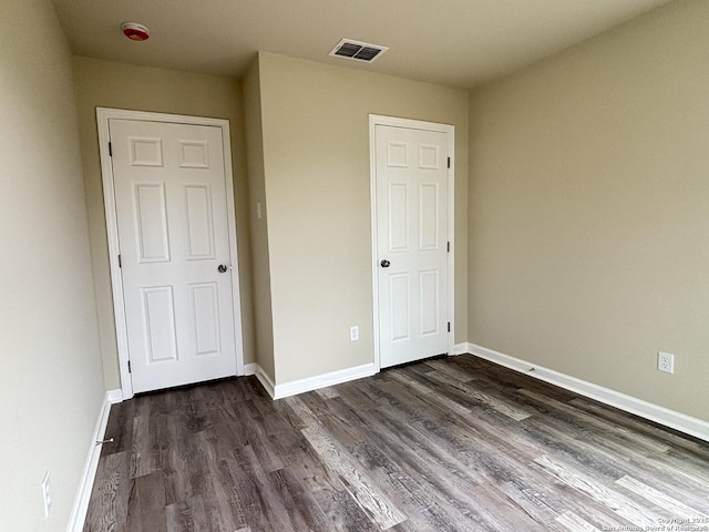 708 E 5th, Nixon, TX 78140 - unfurnished bedroom with visible vents, baseboards, and dark wood-type flooring