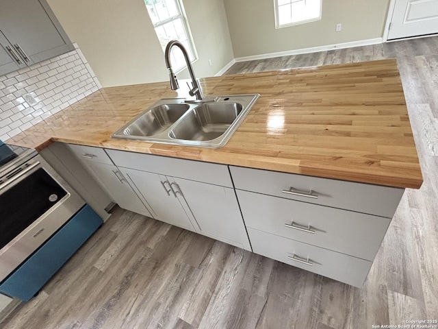 708 E 5th, Nixon, TX 78140 - kitchen featuring a sink, wood counters, wood finished floors, and tasteful backsplash