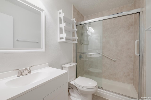 bathroom featuring a stall shower, toilet, a textured ceiling, and vanity