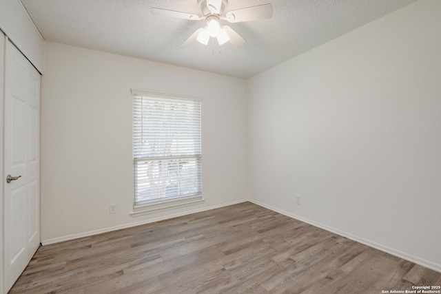interior space featuring wood finished floors, a closet, baseboards, and multiple windows