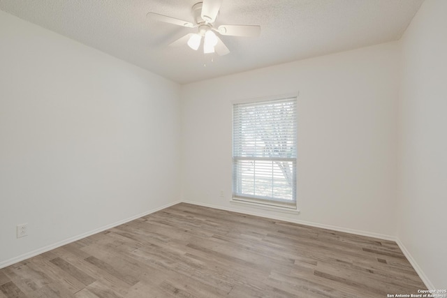 empty room with a textured ceiling, ceiling fan, light wood-type flooring, and baseboards