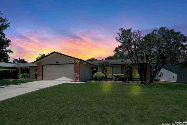 single story home featuring driveway, a yard, an attached garage, and brick siding