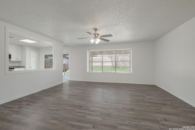 unfurnished living room featuring a textured ceiling, a ceiling fan, baseboards, and dark wood-type flooring