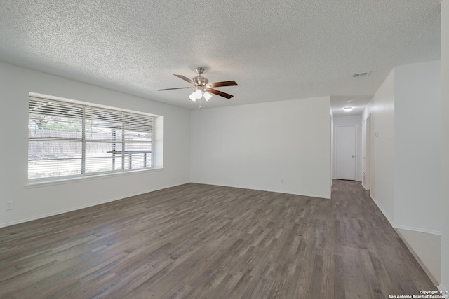 empty room featuring a textured ceiling, wood finished floors, a ceiling fan, and visible vents