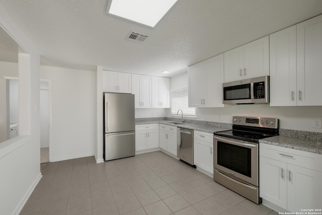 kitchen featuring a sink, stainless steel appliances, visible vents, white cabinetry, and a textured ceiling