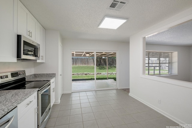kitchen with stainless steel appliances, light tile patterned flooring, visible vents, white cabinetry, and a textured ceiling