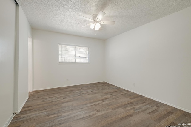 empty room featuring a ceiling fan, baseboards, wood finished floors, and a textured ceiling