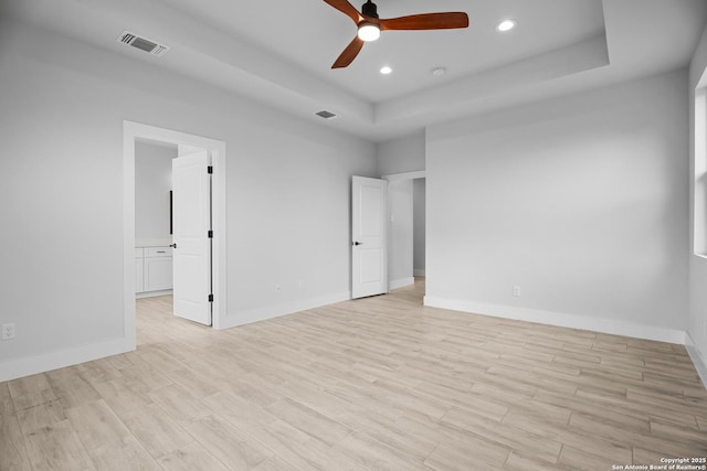 unfurnished bedroom with a raised ceiling, visible vents, recessed lighting, and light wood-style floors
