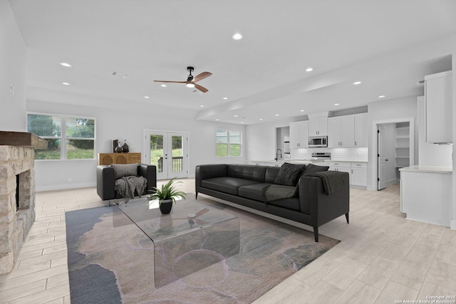 living room with ceiling fan, french doors, recessed lighting, and a stone fireplace