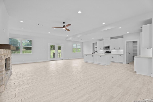 unfurnished living room featuring recessed lighting, a sink, a fireplace, ceiling fan, and baseboards