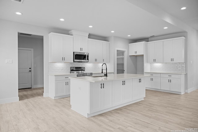 kitchen featuring recessed lighting, a sink, backsplash, baseboards, and appliances with stainless steel finishes