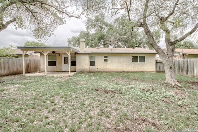 rear view of property with a chimney, stucco siding, a fenced backyard, and a patio area