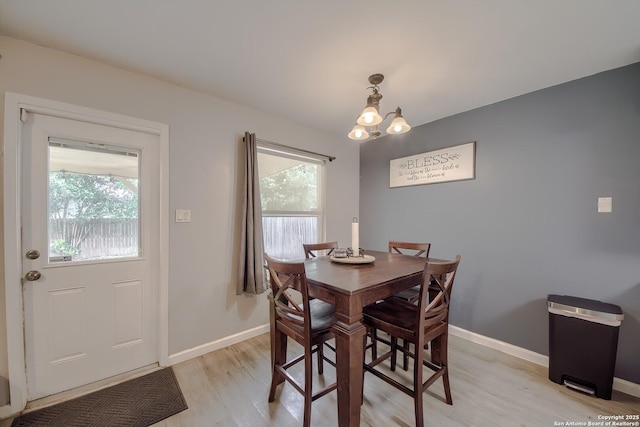 dining space with a chandelier, light wood-style flooring, and baseboards