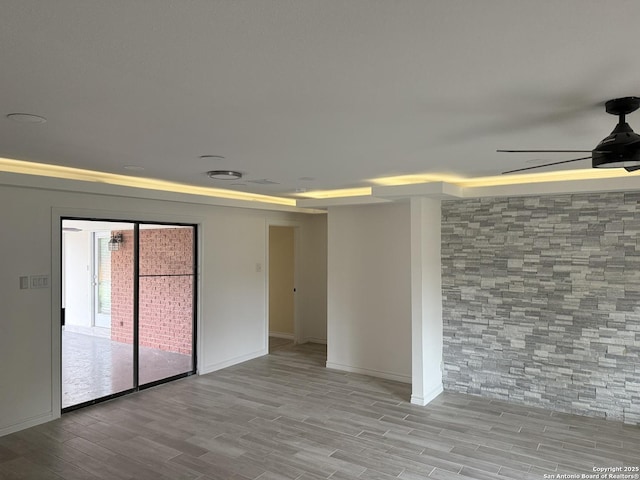 unfurnished room with a ceiling fan, wood finished floors, and baseboards