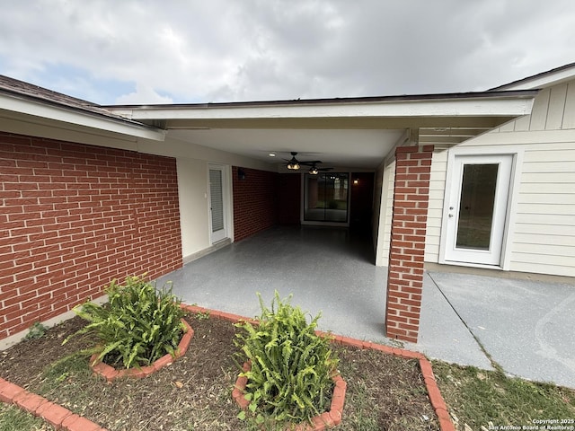 view of exterior entry with a ceiling fan, a patio area, and brick siding