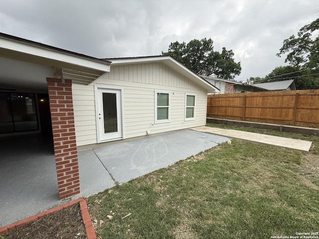 rear view of property with fence, a yard, and a patio area