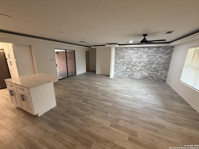 unfurnished living room with wood finished floors, visible vents, a ceiling fan, and baseboards