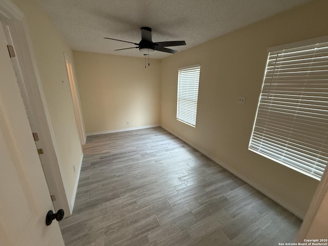 spare room with baseboards, wood finished floors, a ceiling fan, and a textured ceiling