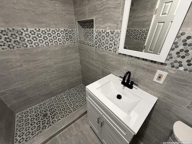 bathroom with toilet, vanity, tile walls, and tiled shower