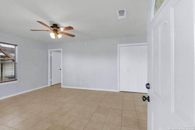 empty room featuring ceiling fan, visible vents, and baseboards