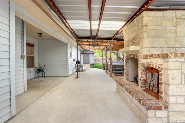 view of patio / terrace with fence, a storage unit, an outbuilding, and a hot tub