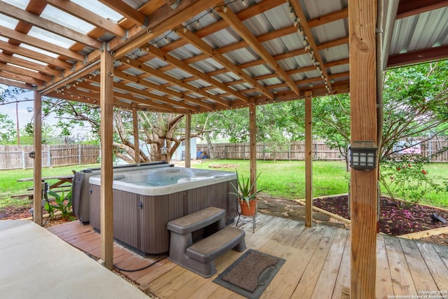 wooden deck with a fenced backyard, a hot tub, and a lawn