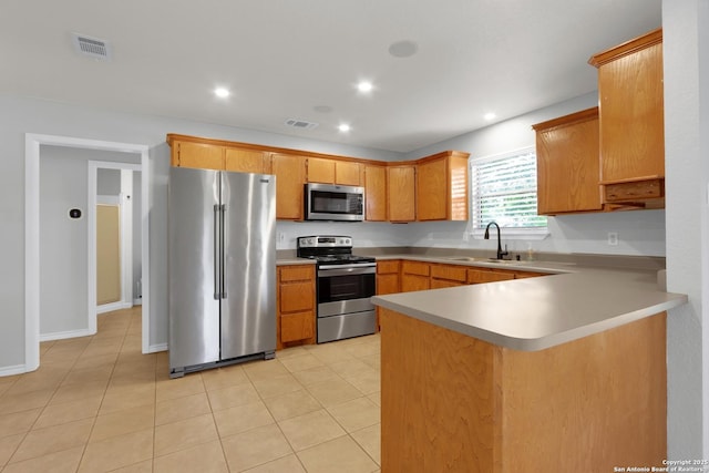 kitchen with a sink, appliances with stainless steel finishes, visible vents, light countertops, and a peninsula