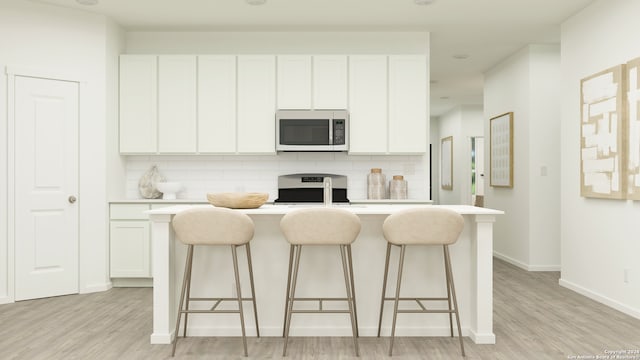 kitchen with tasteful backsplash, range, a breakfast bar area, light countertops, and white cabinets