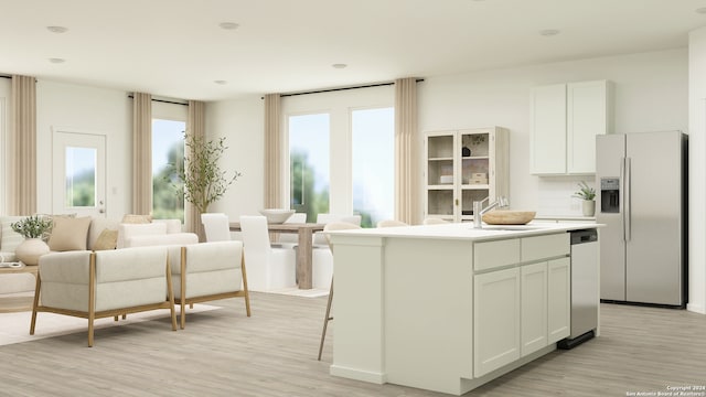 kitchen with white cabinetry, a sink, appliances with stainless steel finishes, a center island, and light wood finished floors