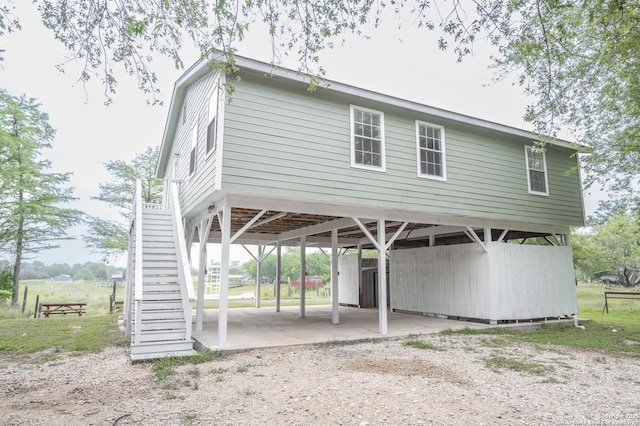 view of parking / parking lot featuring stairs, dirt driveway, and a carport