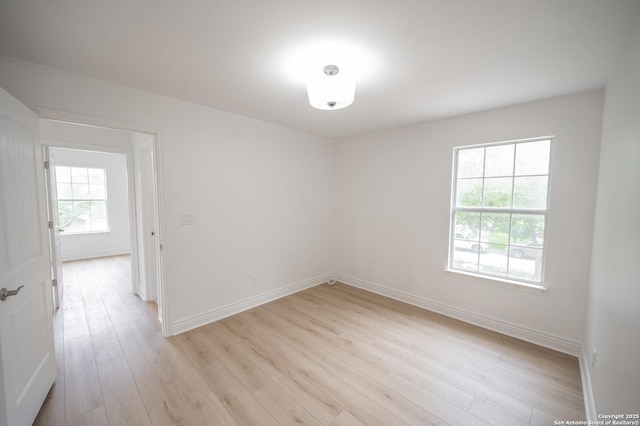 unfurnished room featuring baseboards and light wood-style floors
