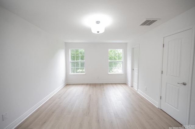 unfurnished room featuring baseboards, visible vents, and light wood-style floors
