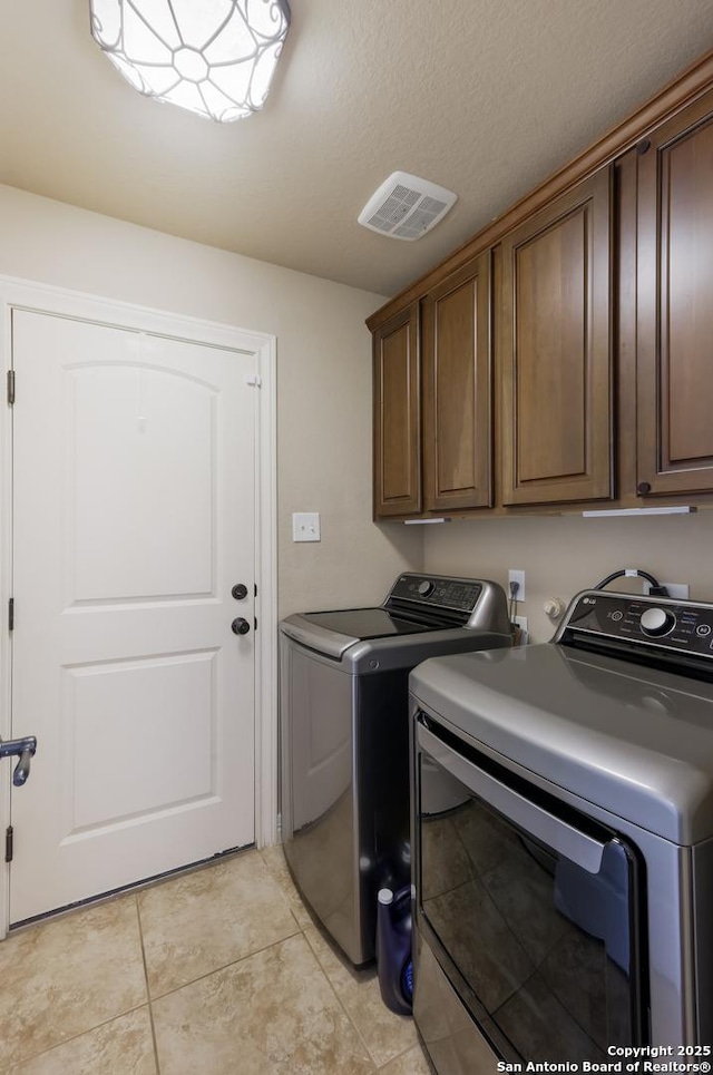 laundry room with light tile patterned flooring, cabinet space, separate washer and dryer, and visible vents